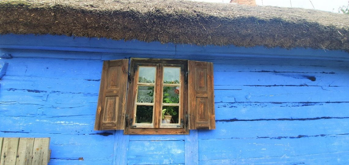 Chałupa z Czermna pomalowana na niebiesko, zbliżenie na ścianę i drewniane okno - Skansen w Sierpcu