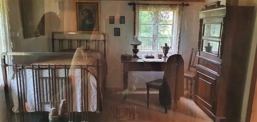 Dawna izba, chałupa wyposażona w łóżko, regał, biurko i krzesło - Muzeum Wsi Mazowieckiej w Sierpcu