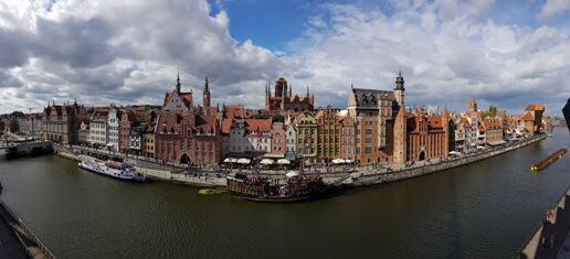 Panorama Gdańska w pochmurny dzień. Na zdjęciu Czarna Perła, Bayzilka Mariacki, Motława. Zdjęcie panoramiczne. Autor © Łukasz Suska