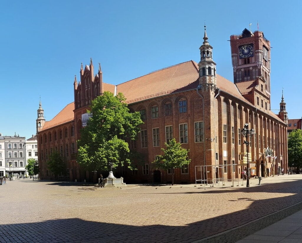 Toruń - widok na Ratusz Staromiejski zbudowany z czerwonej cegły. Bezchmurne niebo nad budynkiem.